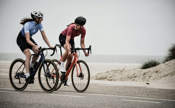 man and woman riding road bikes at the road near shore