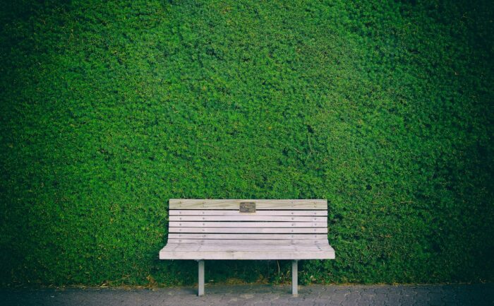 empty white wooden bench beside green wall