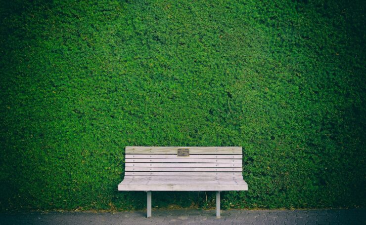 empty white wooden bench beside green wall